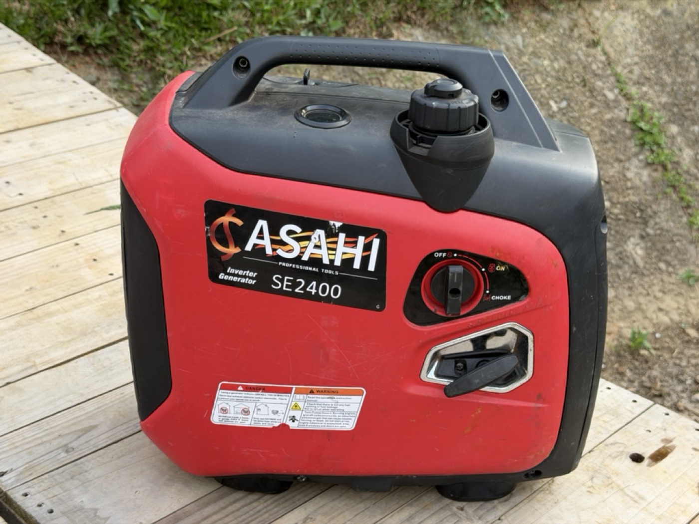 台北露營車出租｜紅色便攜式外置發電機 ASAHI SE2400 Inverter Generator 外觀，放置於木棧板上，可搭配延長線拉到遠處運轉，夜間在海邊或非露營區過夜開冷氣時不會吵到車內