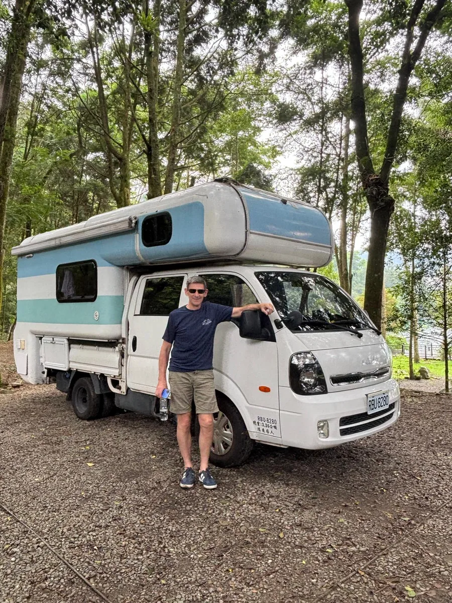化名 Daniel 的住澳洲英國旅人與露營車合影，象徵第一次台灣環島公路旅行留下的快樂回憶