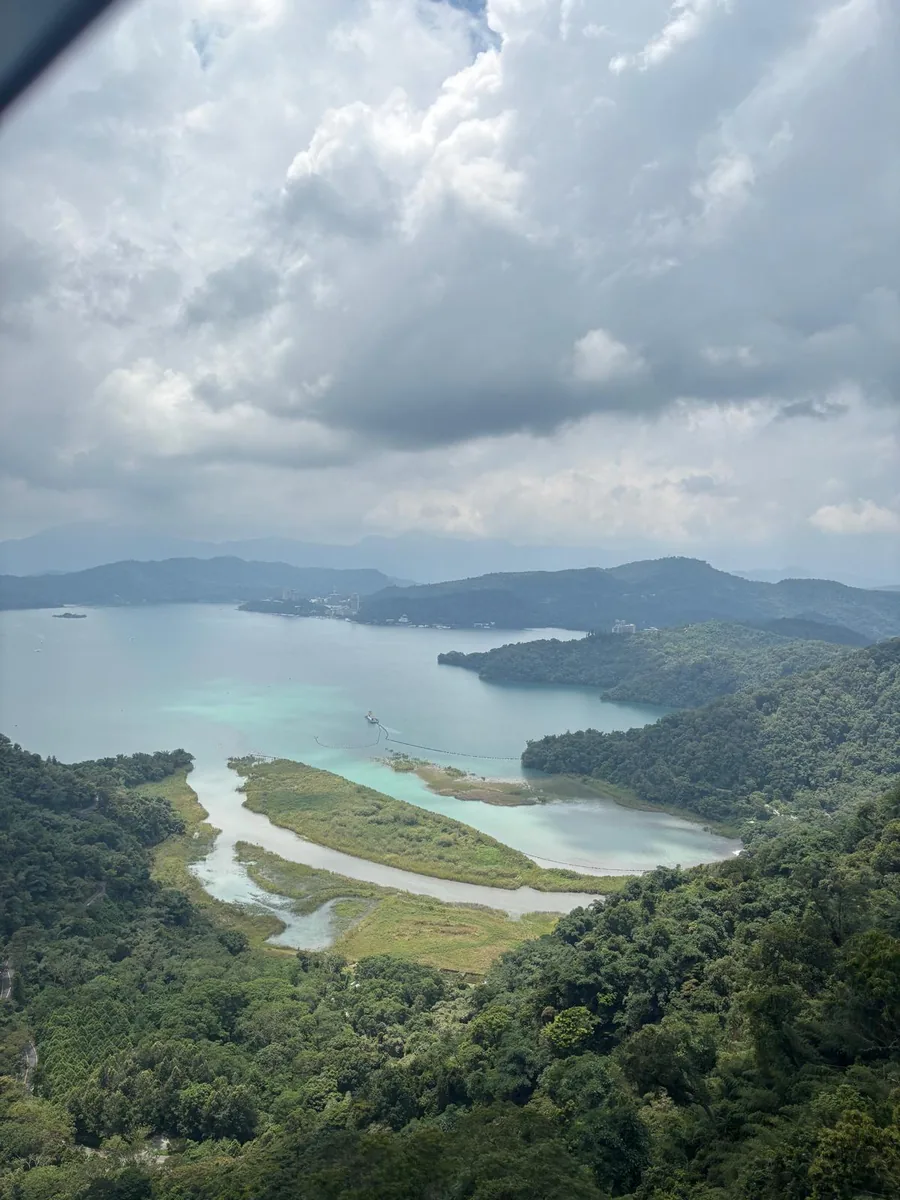 從日月潭纜車高處俯瞰群山與湛藍湖面，呈現國際旅客在台灣露營車旅行中的湖泊景點體驗