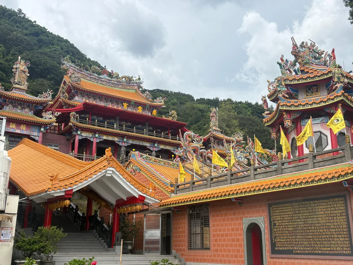 英國旅人的台灣露營車旅行途中，海岸廟宇與翠綠山脈在晴朗天空下交會，呈現台灣自然與人文風景