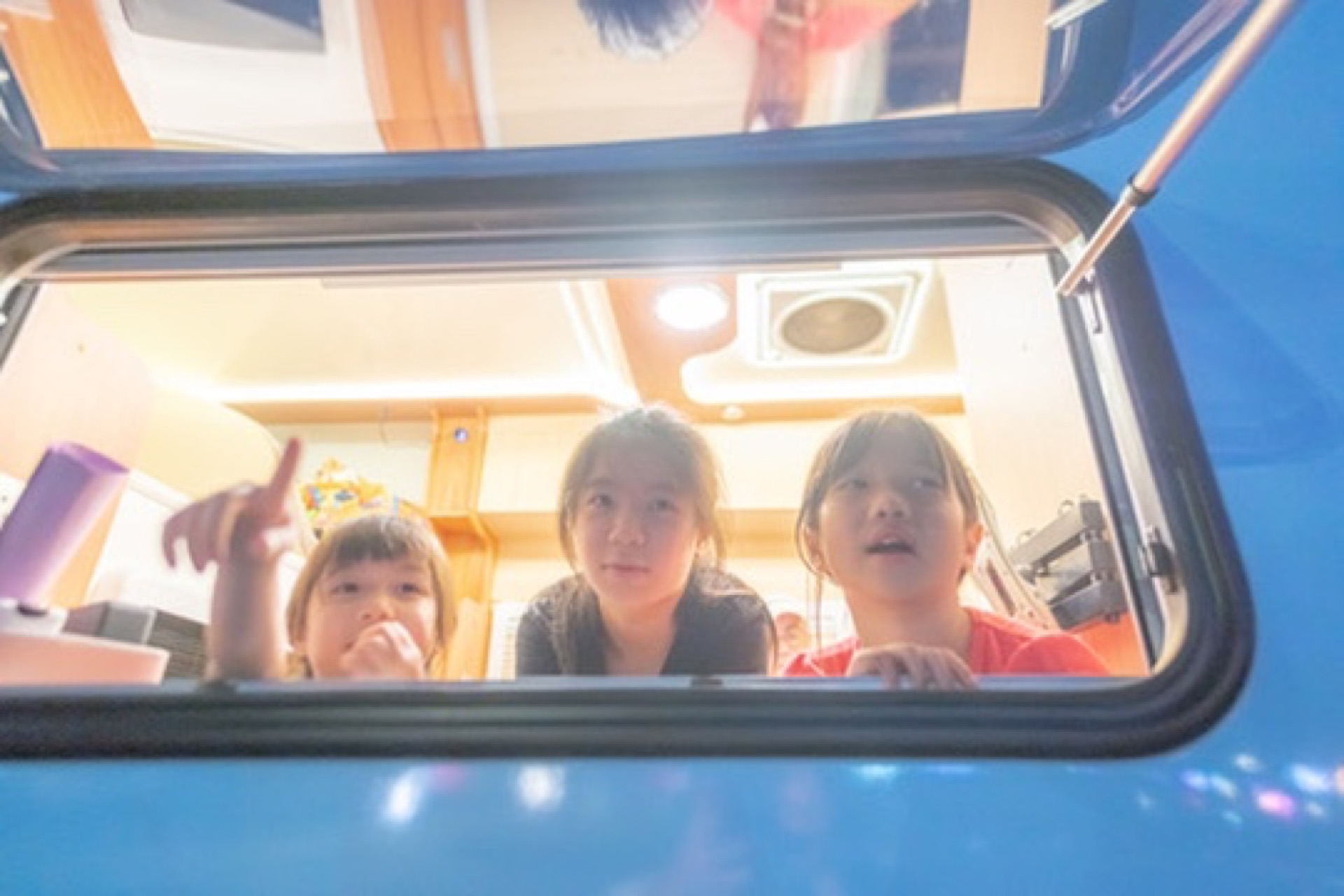 Child leaning from campervan side window smiling—warm family first-timer campervan planning scene