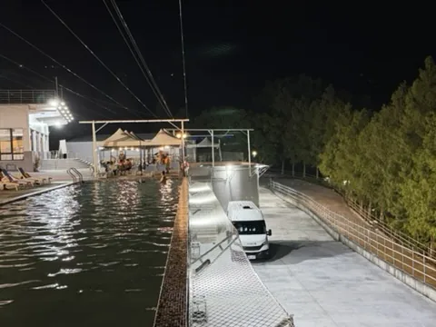 夜間溫泉池旁停放一輛白色露營車，呈現關子嶺泡湯與露營車過夜的實際情境