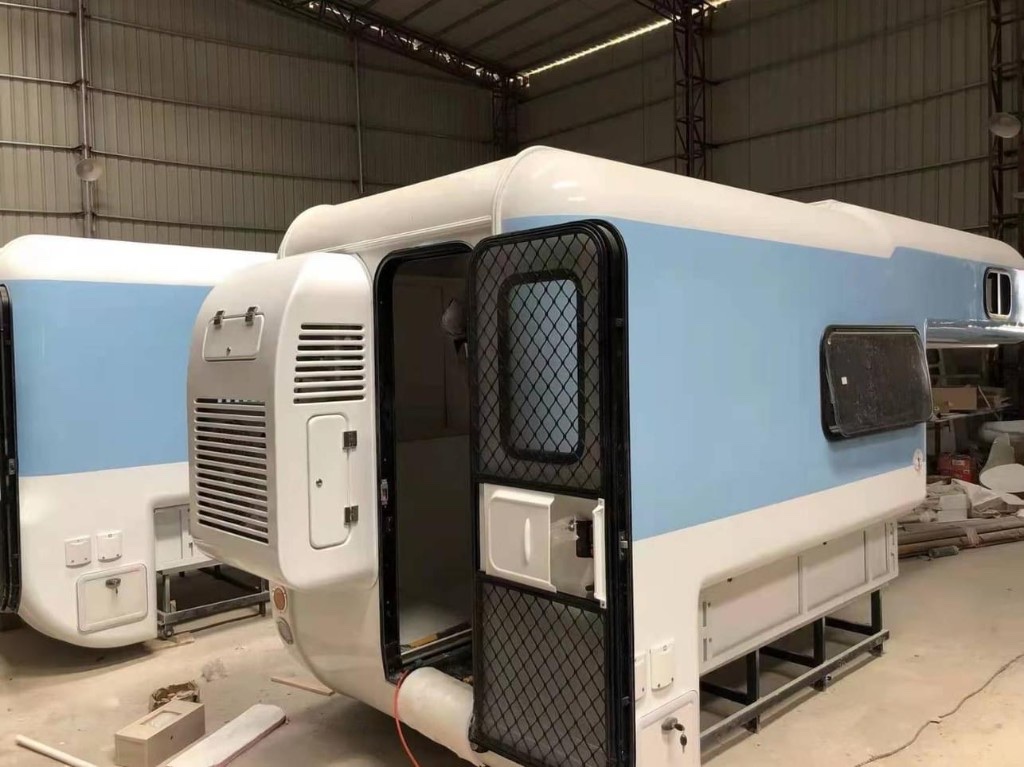 Joyforest campervan factory assembly: white-and-blue body on build stand, side door open—dream taking shape on site