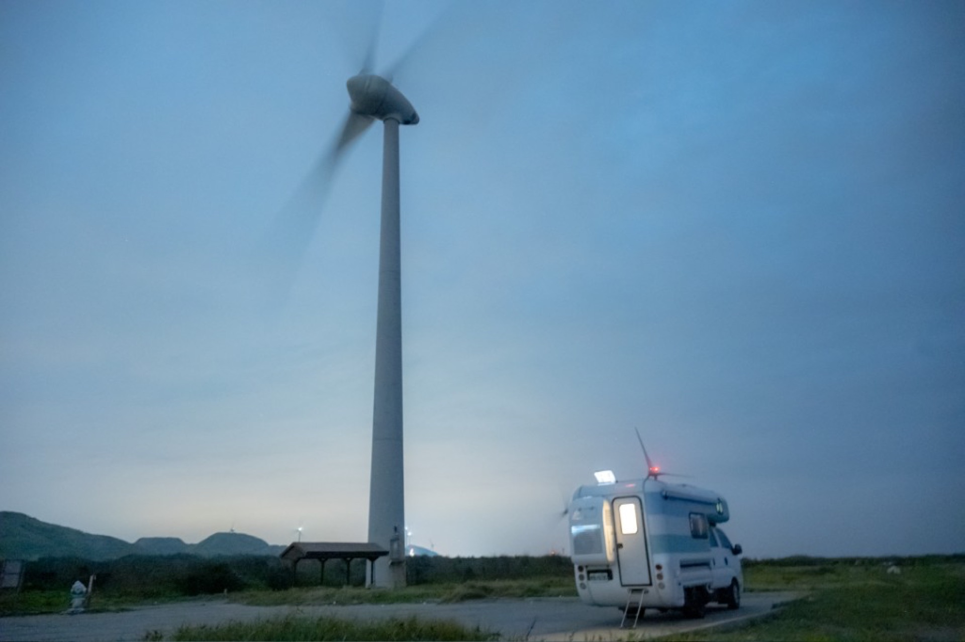 苗栗海線暮色中露營車與風力發電機同框的車宿氛圍
