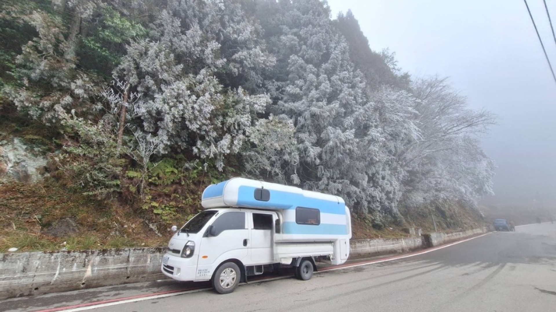 White-and-blue campervan beside rime-ice forest on the Wuling mountain highway—Central Cross-Island and highland overnight trip