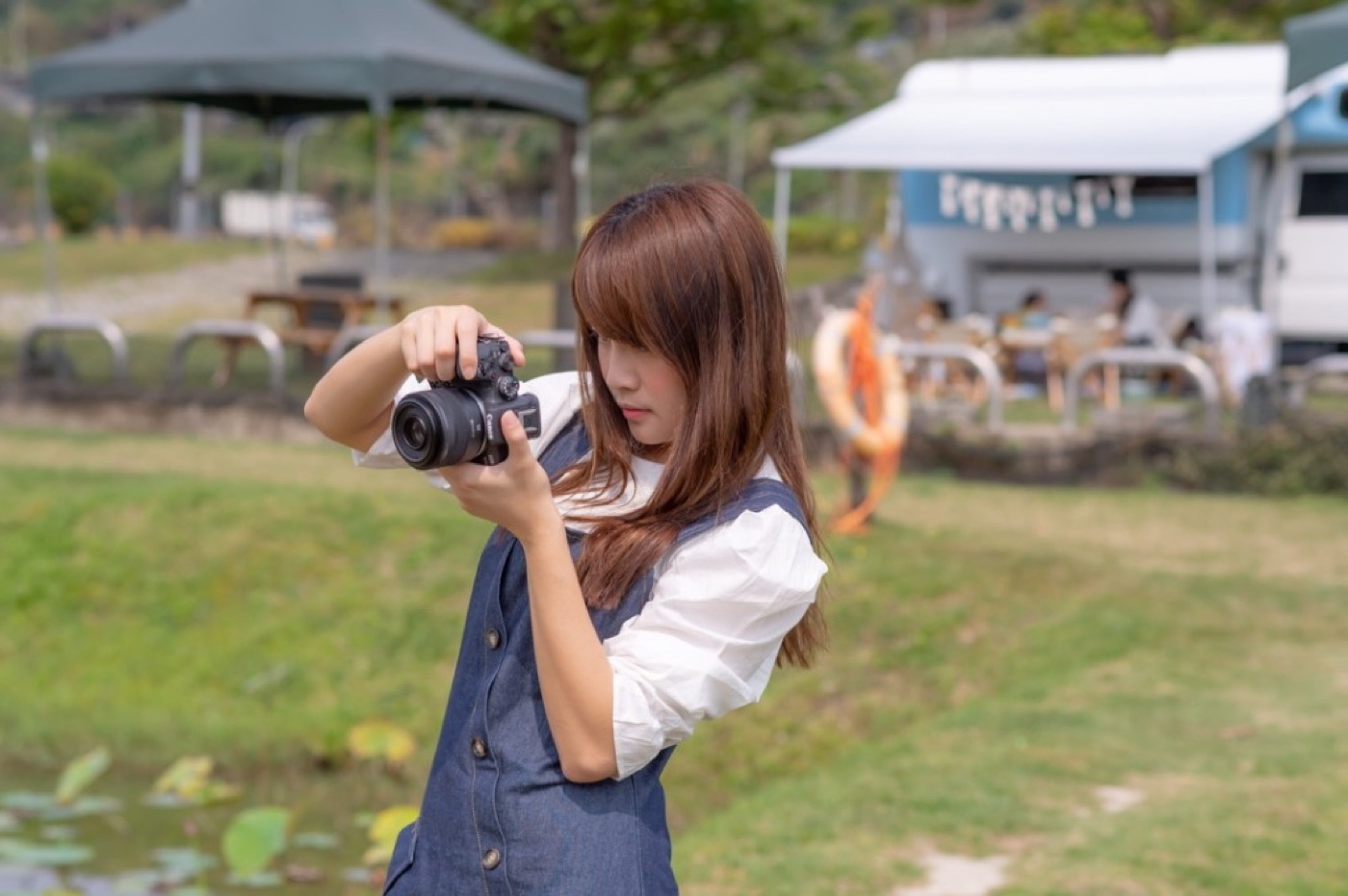 Rakuten Girls member framing shot on green camp pitch, blue-white campervan white awning outdoor setup background