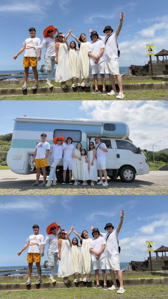 七位年輕旅人穿白色夏裝，在海岸石牆與藍白露營車前開心合影，海邊過夜的露營車好友旅行